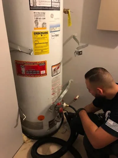 Plumber inspecting residential water heater tank connections and valves