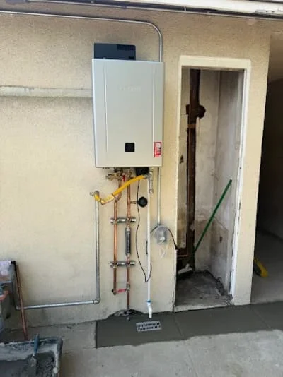 Tankless water heater mounted on wall with gas and water line connections