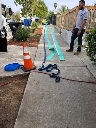 Technician performing sewer line camera inspection on residential driveway with marked diagnostic line